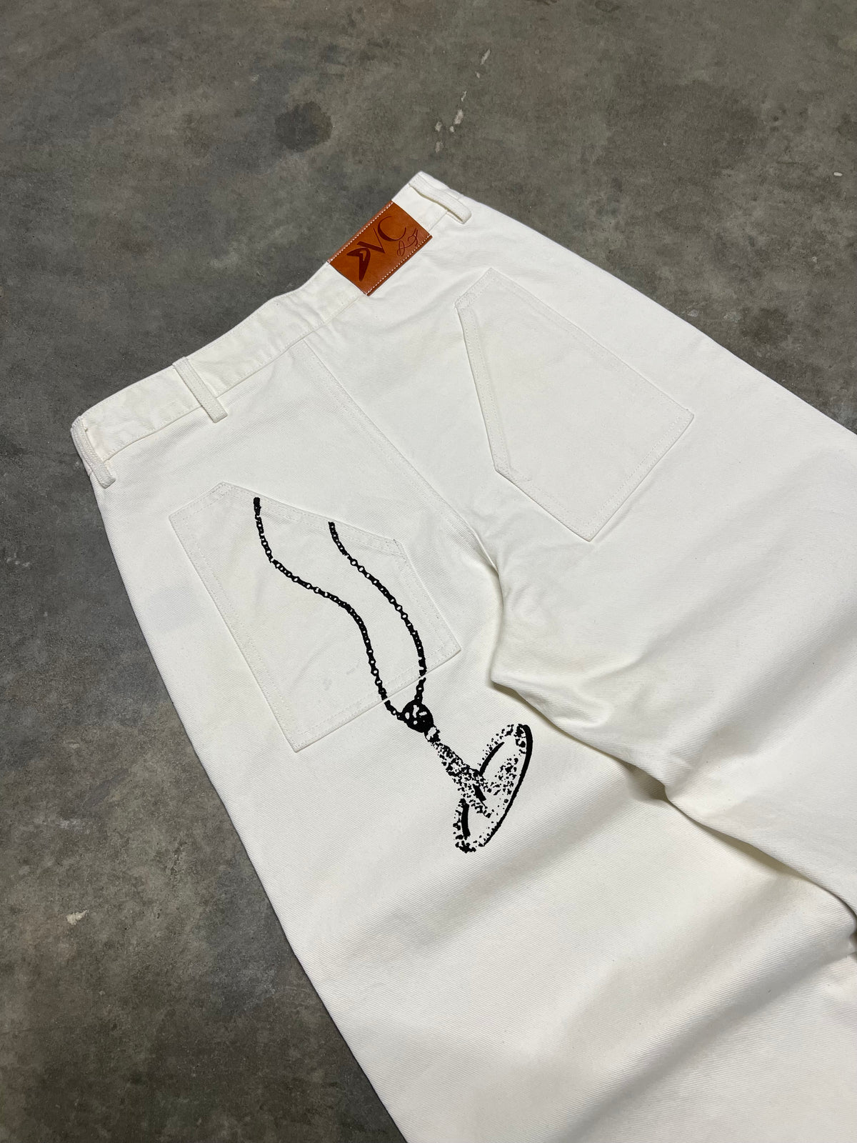 Jean blanc signature DIVICE – détail du collier DIVICE dessiné sur la poche arrière et étiquette en cuir orange