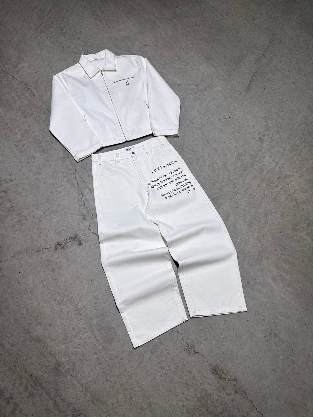 Veste blanche signature DIVICE – posée à plat avec le jean blanc