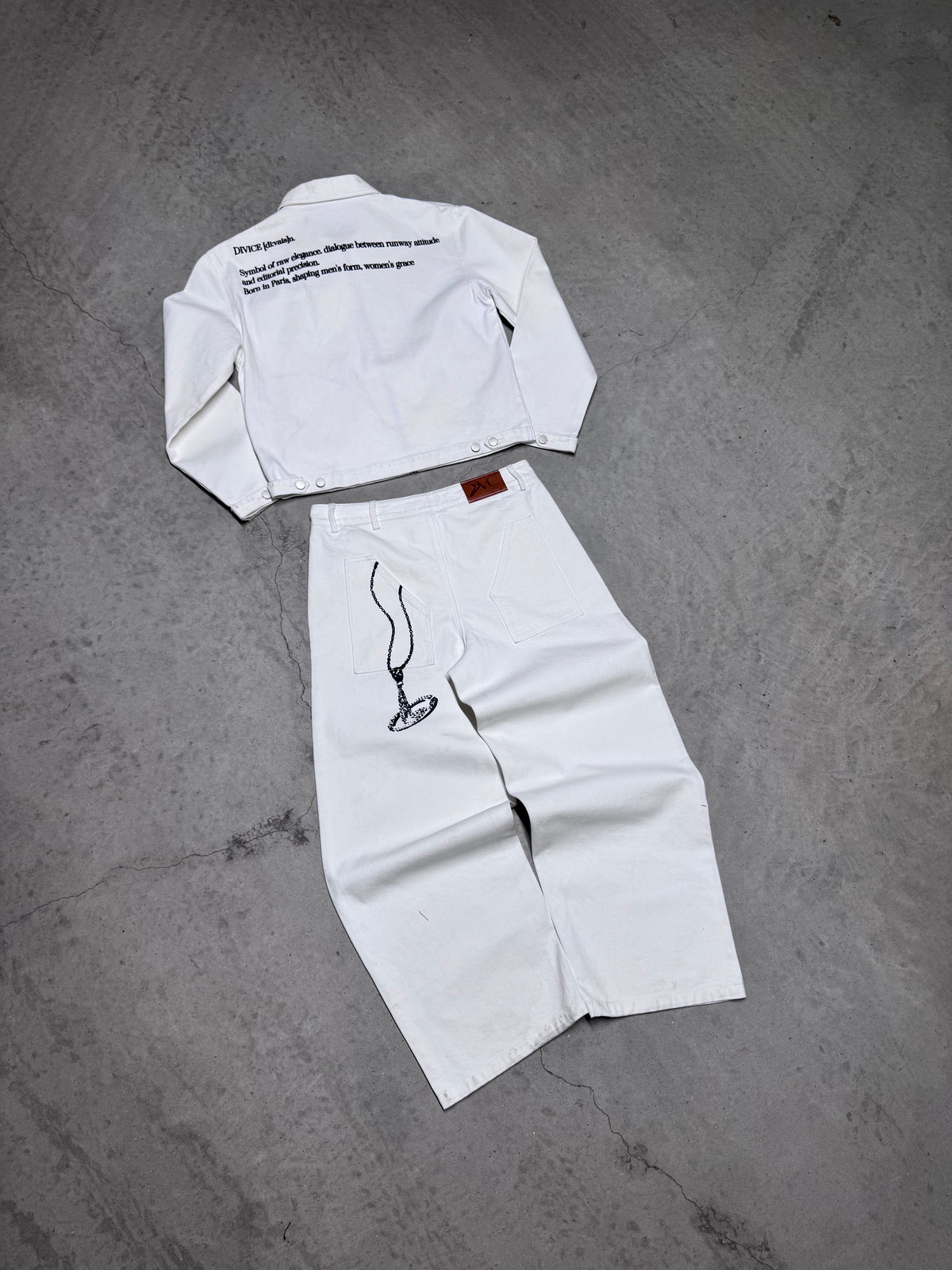Veste blanche signature DIVICE – posée à plat, vue de dos avec le jean blanc